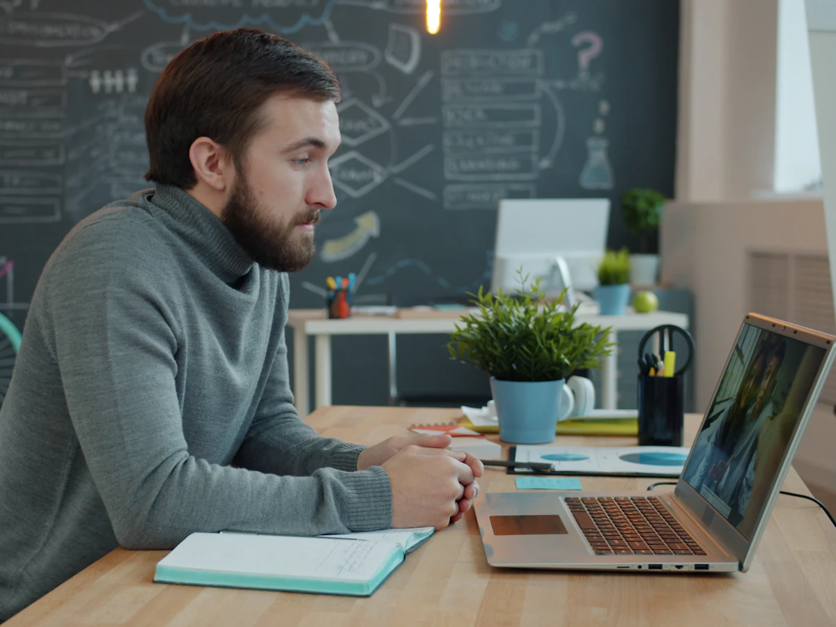 A working professional attending an online class from their desk